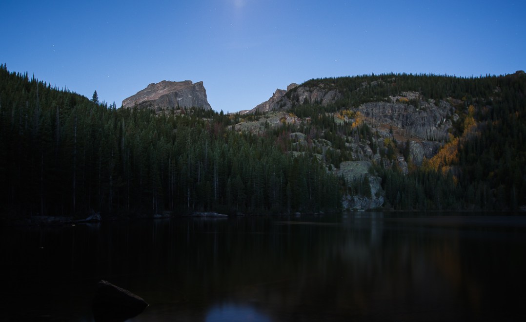 Bear Lake, in Rocky Mountain National Park lit b the moon (center to of frame), and the first rays of sunlight at the point of Astronomical sunrise.